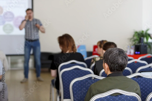 Obraz Spectators listen to the speech in the conference room. The focus is under the person on the front surface