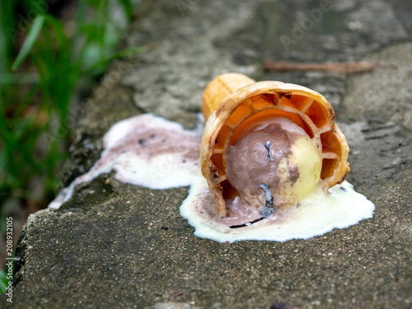 Fototapeta A rainbow ice cream cone dropped on the concrete floor and melting on ground in a summer day. with copy space for text.