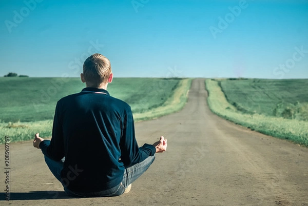 Fototapeta Silence, Lonely man meditating on a deserted road at sunset