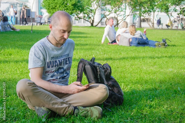 Obraz young man on grass with mobile phone, surfing internet