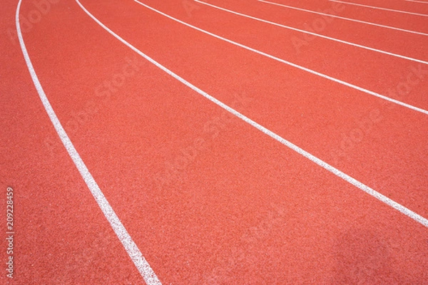 Fototapeta White lines of stadium and texture of running racetrack red rubber racetracks in outdoor stadium are 8 track and green grass field,empty athletics stadium with track.