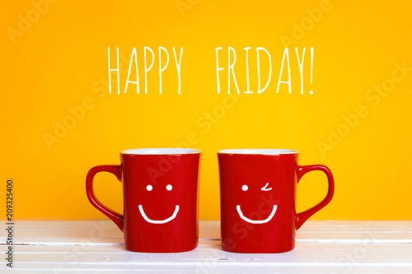 Obraz Dwa czerwone kubki do kawy z uśmiechniętymi twarzami na żółtym tle z napisem Happy Friday.