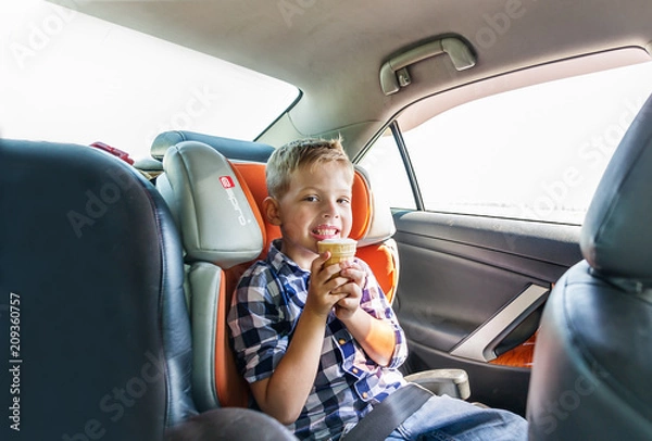 Obraz A small boy eating ice cream, sitting strapped in the car seat
