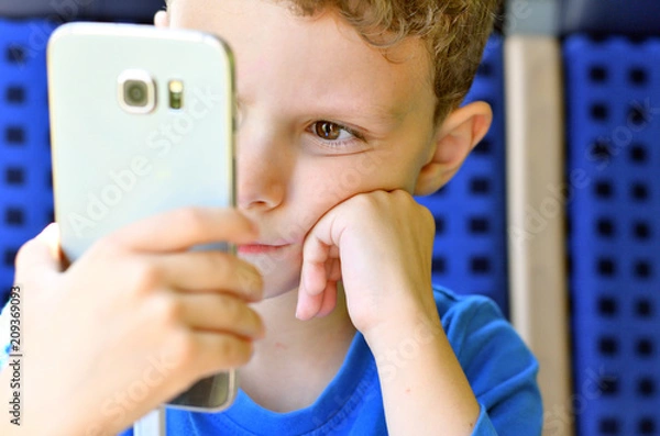 Fototapeta Kleiner Junge spielt mit Smartphone auf einer Zugfahrt