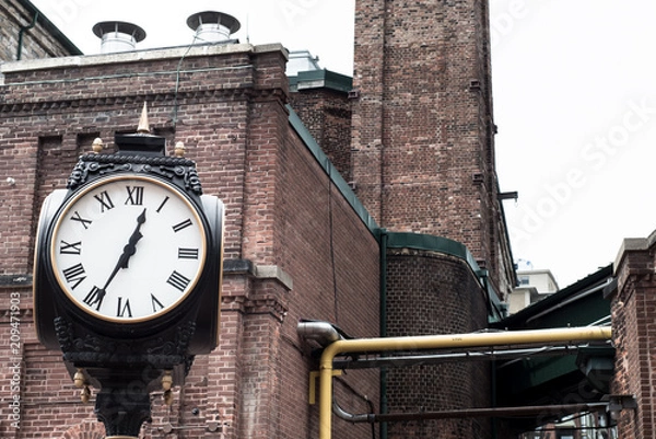 Obraz Analog Clock with brick buildings in the background
