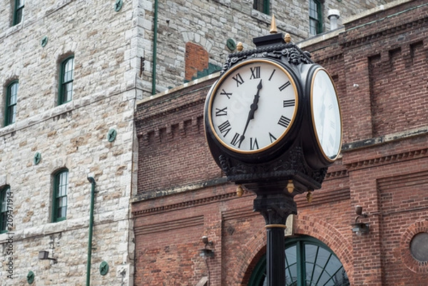 Obraz Analog Clock with brick buildings in the background