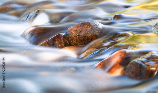 Fototapeta Long exposure of a small stream gently flowing over rounded rocks in the Cathedral Range State Park, Victoria, Australia.