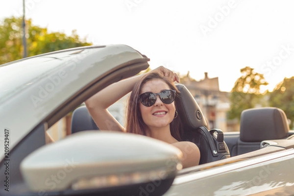 Fototapeta Beautiful girl in the  convertible cabrio car on a sunny day in a city