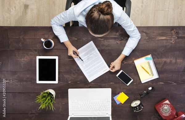 Obraz Businesswoman examining papers at table