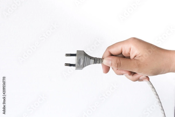 Fototapeta Close up hand inserting an electrical plug into a wall socket