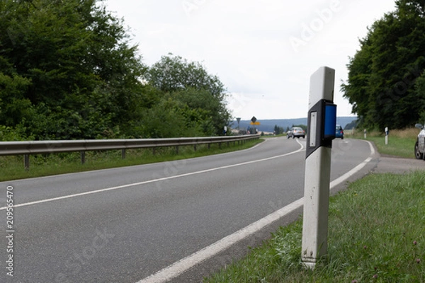 Fototapeta Reflector post with blue reflector for wild animals at the streetside of a road