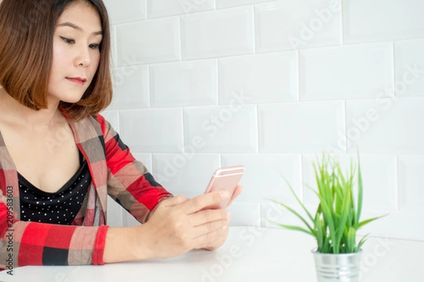 Fototapeta young woman working from home using smart phone, woman's hands using smart phone in interior, man at his workplace using technology