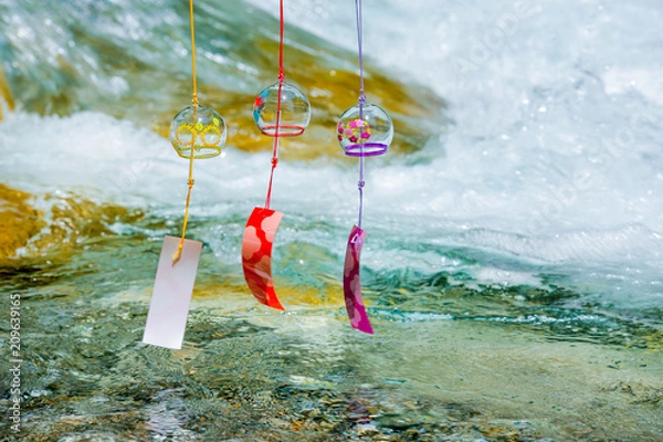 Fototapeta Japanese wind chimes with clean stream on the mountain river in the background.