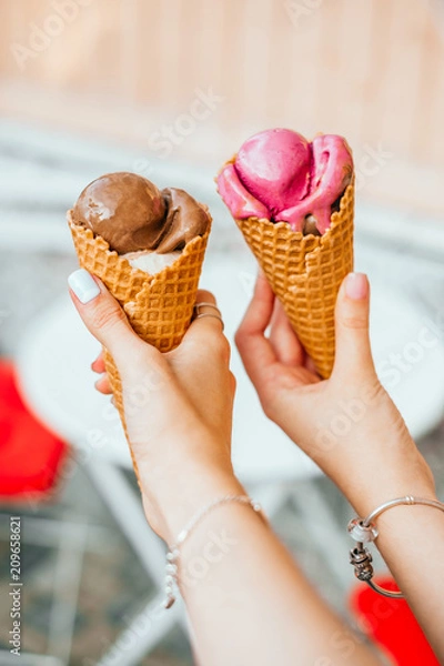 Fototapeta Chocolate and strawberry ice cream in waffle cups in hands of two girls best friends.