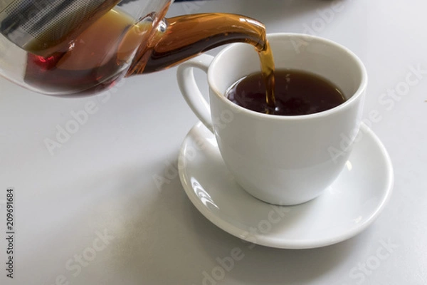 Obraz From a glass teapot tea pours into a mug