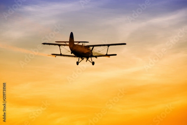 Obraz Biplane flying in vibrant sunset