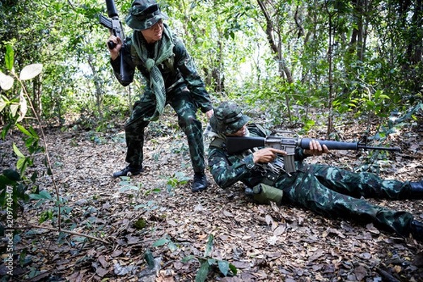 Fototapeta Asian army soldier with weapon during rescue operation evacuate injured fellow at across the deep forest.