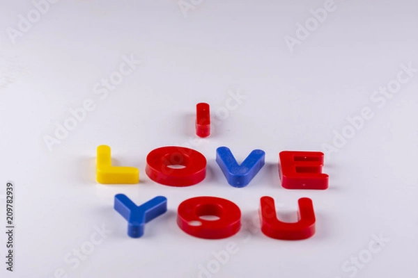 Fototapeta colored uppercase letters isolated forming the phrase i love you made of plastic on white background with shadows
