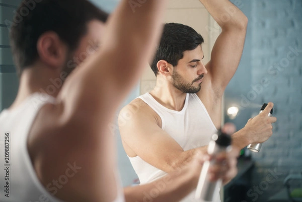 Obraz Man Using Spray Deodorant On Underarm For Bad Smell