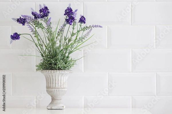 Fototapeta Flowers in a vintage vase are placed on a white table.