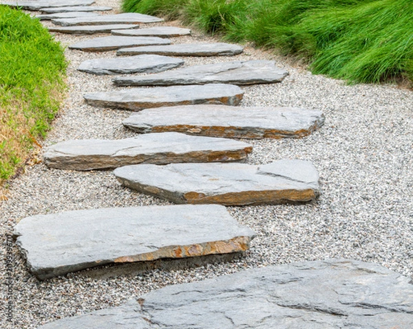 Obraz simple flat stone pathway on gravel surrounded by bright green grass in a Japanese garden