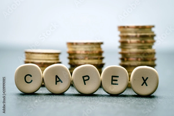 Fototapeta CAPEX letter block and stack coins, business concept. CAPEX stands for Capital Expenditure.