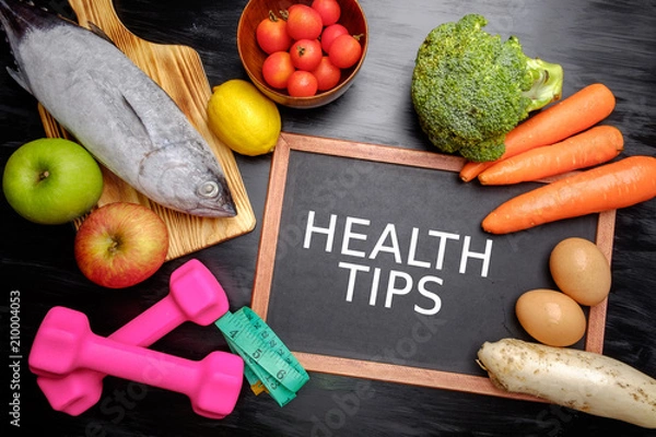 Fototapeta Health Tips, health conceptual. Healthy fresh low carbohydrates food; egg, fish, lemon, tomatoes, apple, carrot and broccoli with dumbbell and measuring tape.