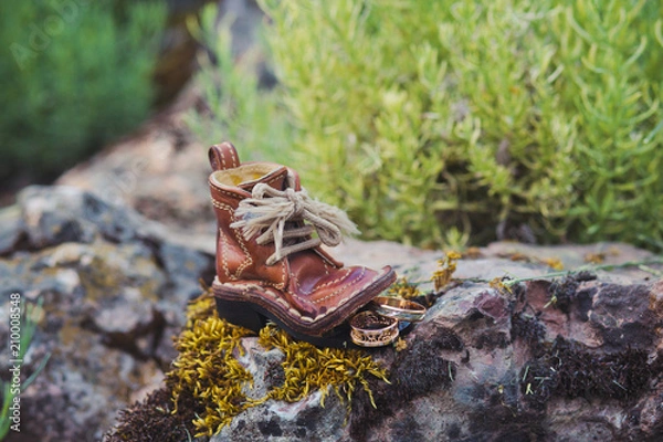 Fototapeta Luxury wedding rings near boot on stone and moss
