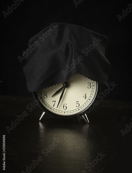 Fototapeta alarm clock on a dark background covered with a cloth.