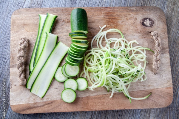 Fototapeta Top view of Courgette prepared on a wooden chopping board. Sliced, julienne and spaghetti