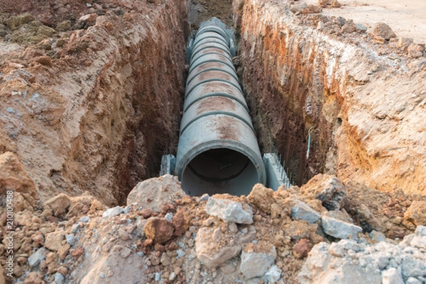 Fototapeta Row of concrete drainage pipe under earth near the construction site.