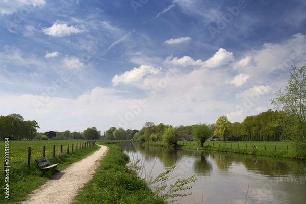 Obraz Authentic Dutch landscape with river Kromme Rijn, walkway, wooden bench, clouds and trees