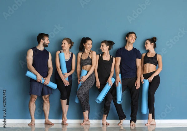 Fototapeta Group of people with yoga mats near color wall