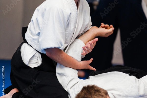 Obraz Aikidoka uses the technique joint lockon the opponent during the training of aikido