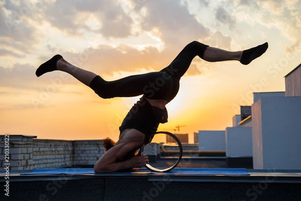 Fototapeta A middle-aged man is engaged in yoga with the use of wheels.