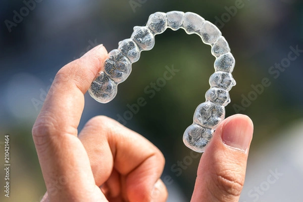 Obraz Holding invisalign braces on bokeh background