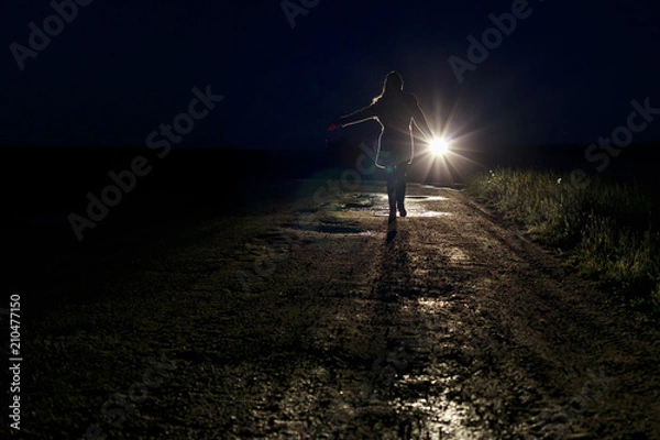 Obraz running scared woman at night in the headlights of a car on a country road silhouette