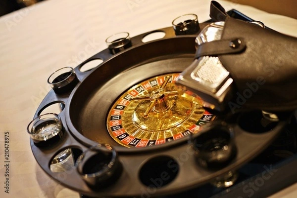 Fototapeta A close up photo of Roulette Drinking Game with shot glasses and blurred pistol grip. Bet and play the dangerous, exciting party game for adults only.