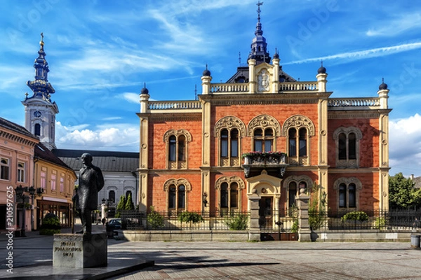 Fototapeta Monument of Jovan Jovanovic Zmaj, in front of and neo-classical architecture of Vladicin Court Palace of Bishop in Novi Sad, Serbia.