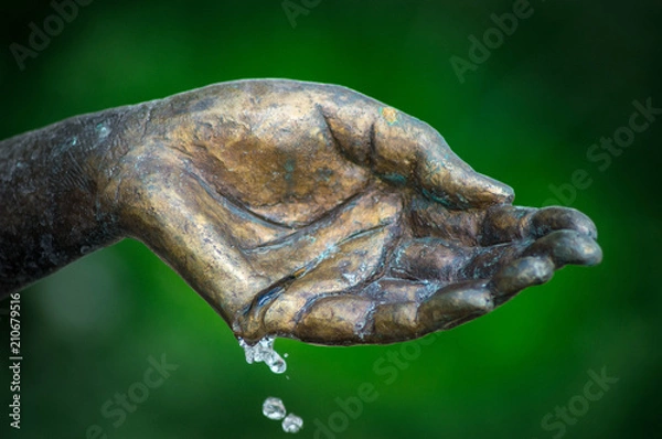Obraz Messing Hand mit Wasser und grünem Hintergrund