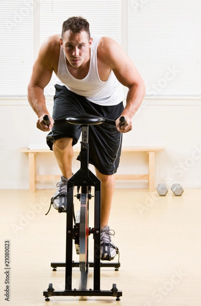 Obraz Man riding stationary bicycle in health club