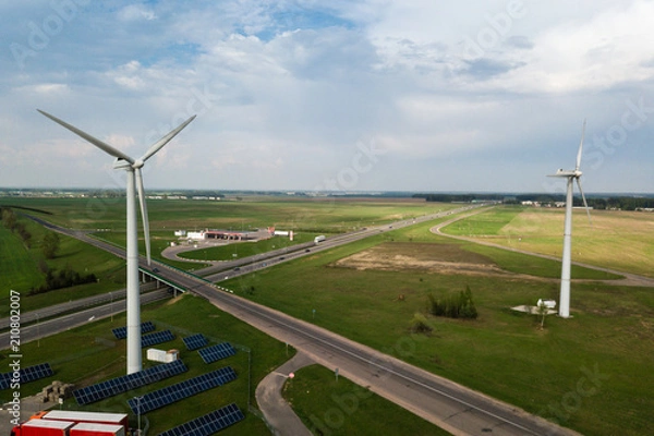 Fototapeta Aerial view of windmills with solar panel on the field on sunny 