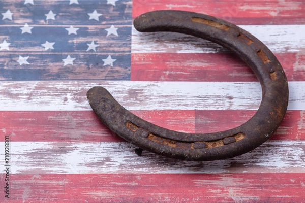 Fototapeta Old rusty horseshoe on USA flag background with room for text