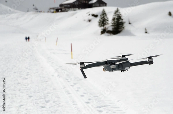 Obraz A camera drone hovering and flying over snowy skiing hills in alps