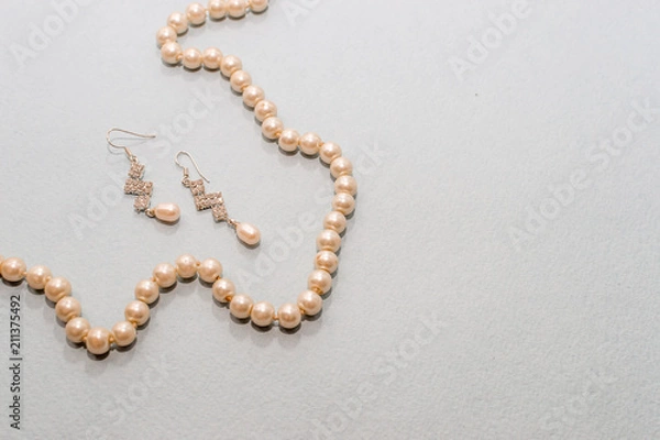 Fototapeta Beads and pearl earrings on a blue background, top view