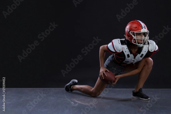 Fototapeta Sexual sportive woman running with rugby ball and screaming aggressively at black background. gender equality