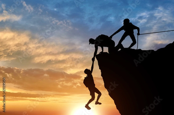 Fototapeta Sylwetka trzech alpinistów ratujących innego wspinacza ciągnącego jego ramię