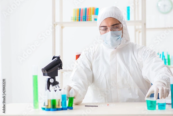 Fototapeta Young chemist student working in lab on chemicals