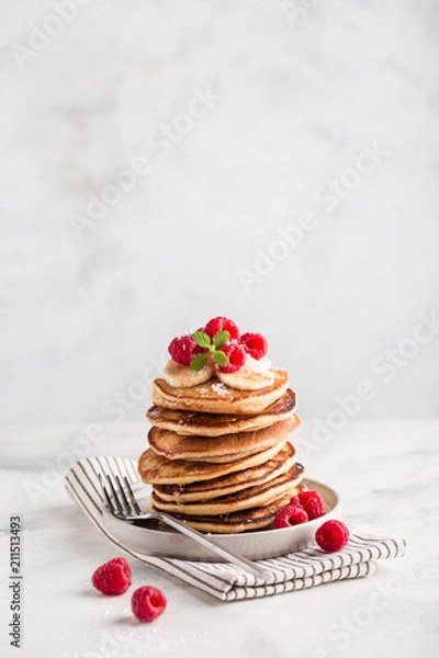 Fototapeta Stack of homemade pancakes with fresh raspberries on light concrete background, copy space