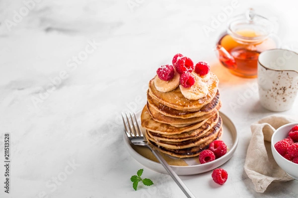 Fototapeta Stack of homemade pancakes with fresh raspberries on light marble background, copy space
